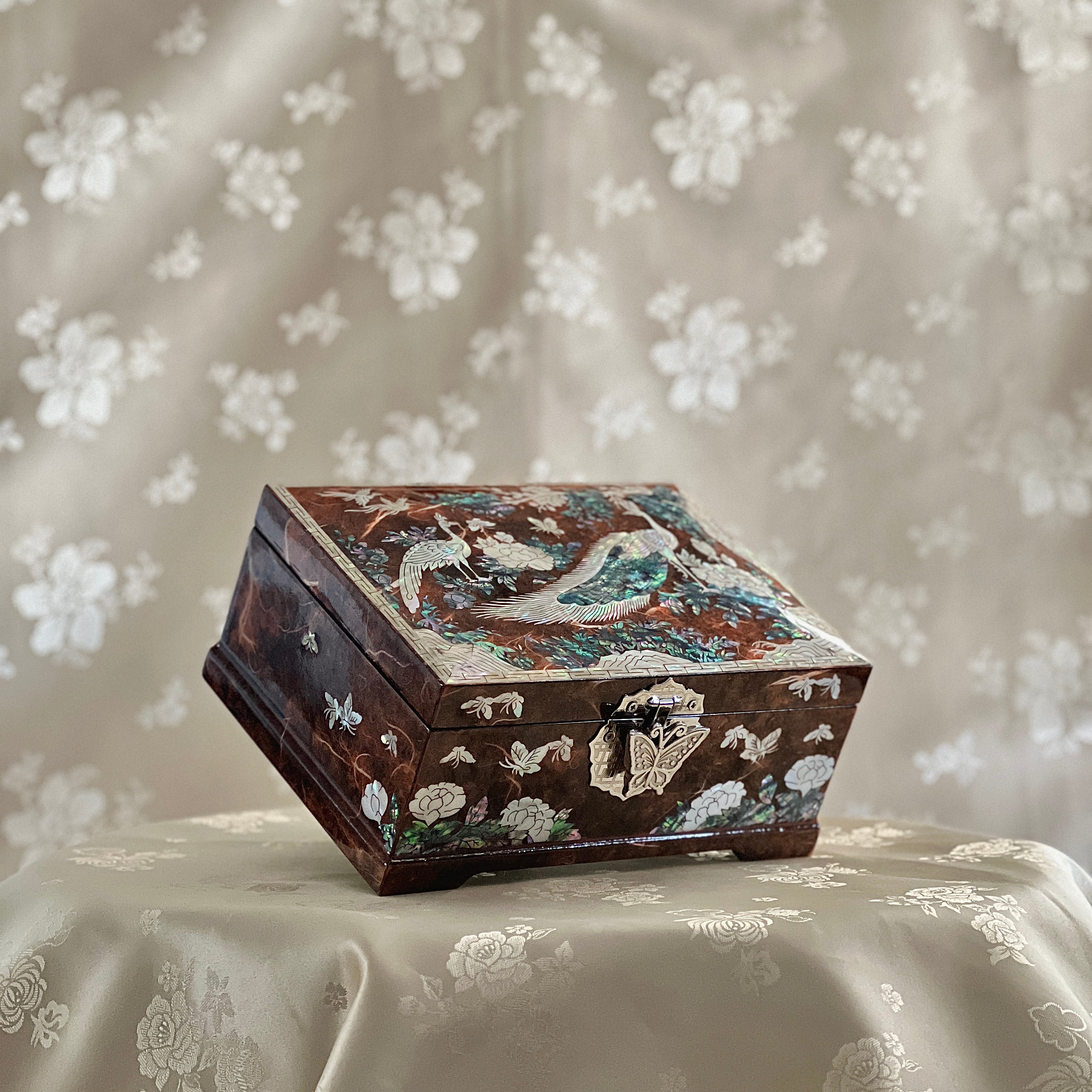 Decorative wooden box with insert for rings on a floral fabric background