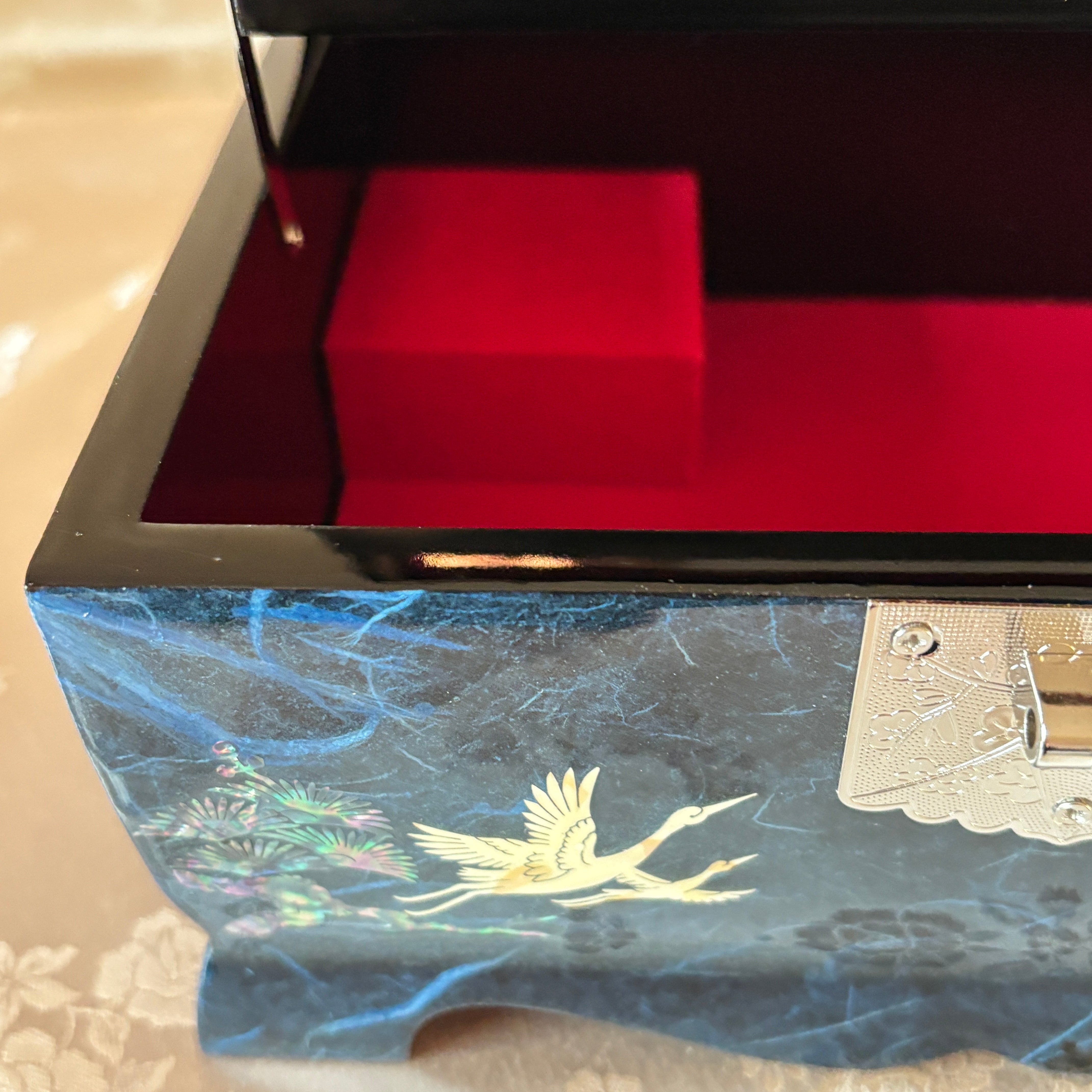 Decorative box with intricate design and red cube on a textured surface