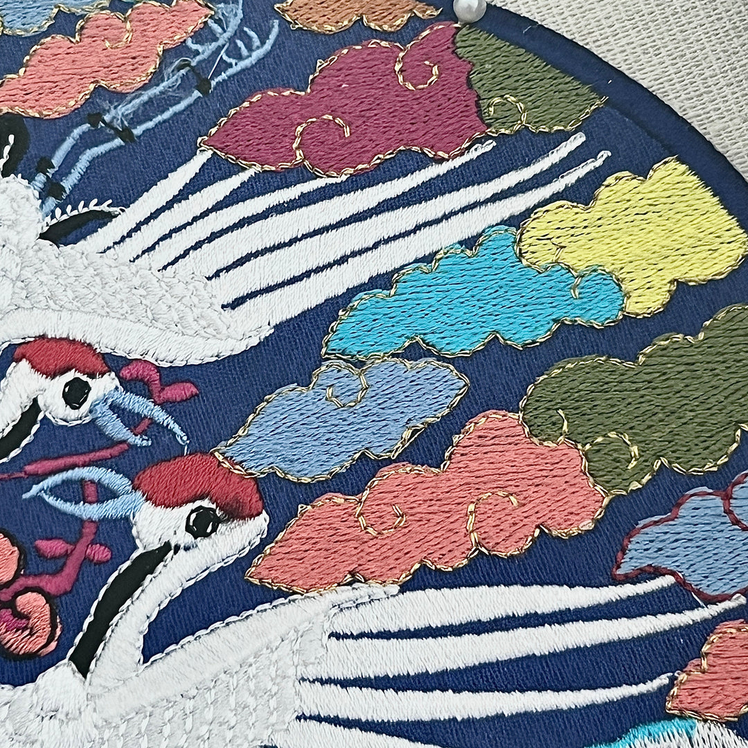 Embroidered design of cranes and clouds on a fabric background