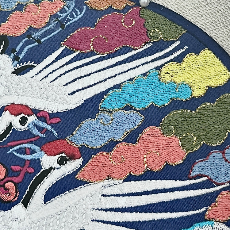 Embroidered design of cranes and clouds on a fabric background
