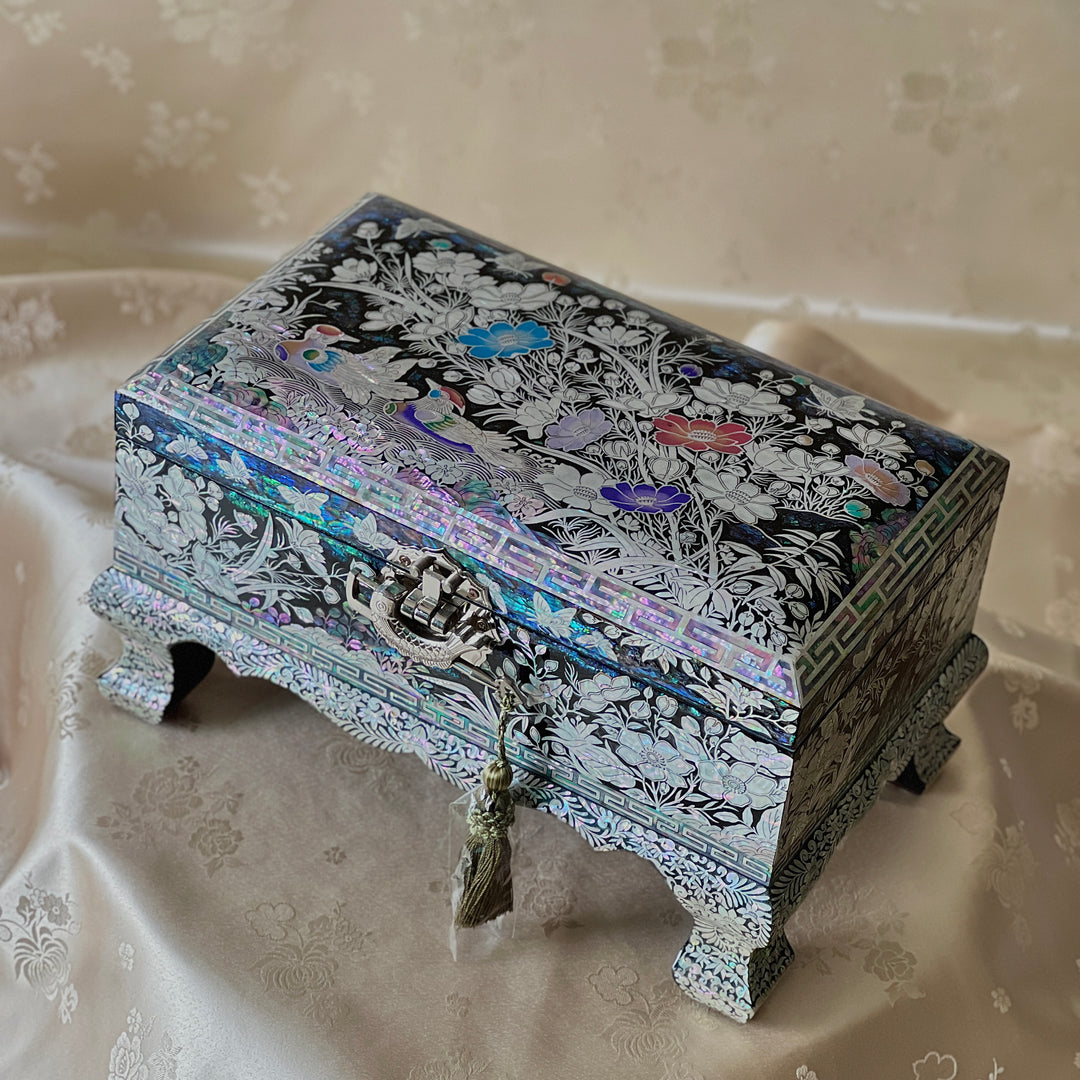 Angled view of a Korean mother-of-pearl legged jewelry box with iridescent shell inlay on black lacquer