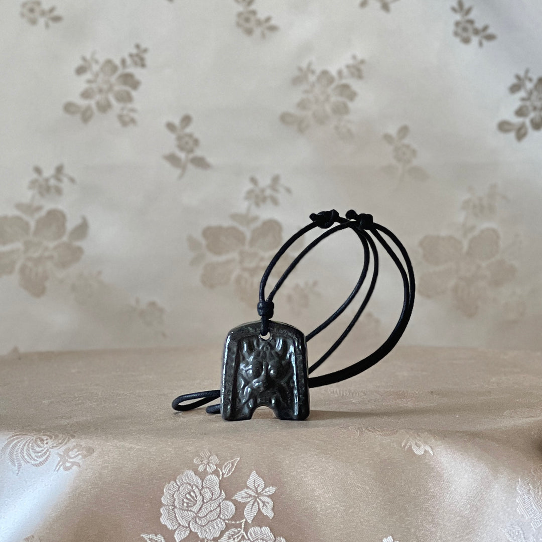 Korean Silla earthenware Gwimyeonwa demon-face pendant necklace shown from the front