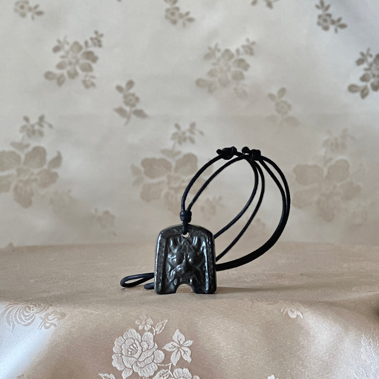 Korean Silla earthenware Gwimyeonwa demon-face pendant necklace shown from the front