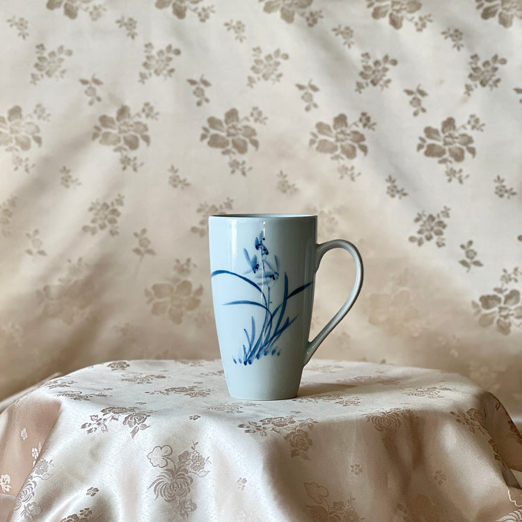 Korean white porcelain mug with blue orchid motif shown upright with handle visible