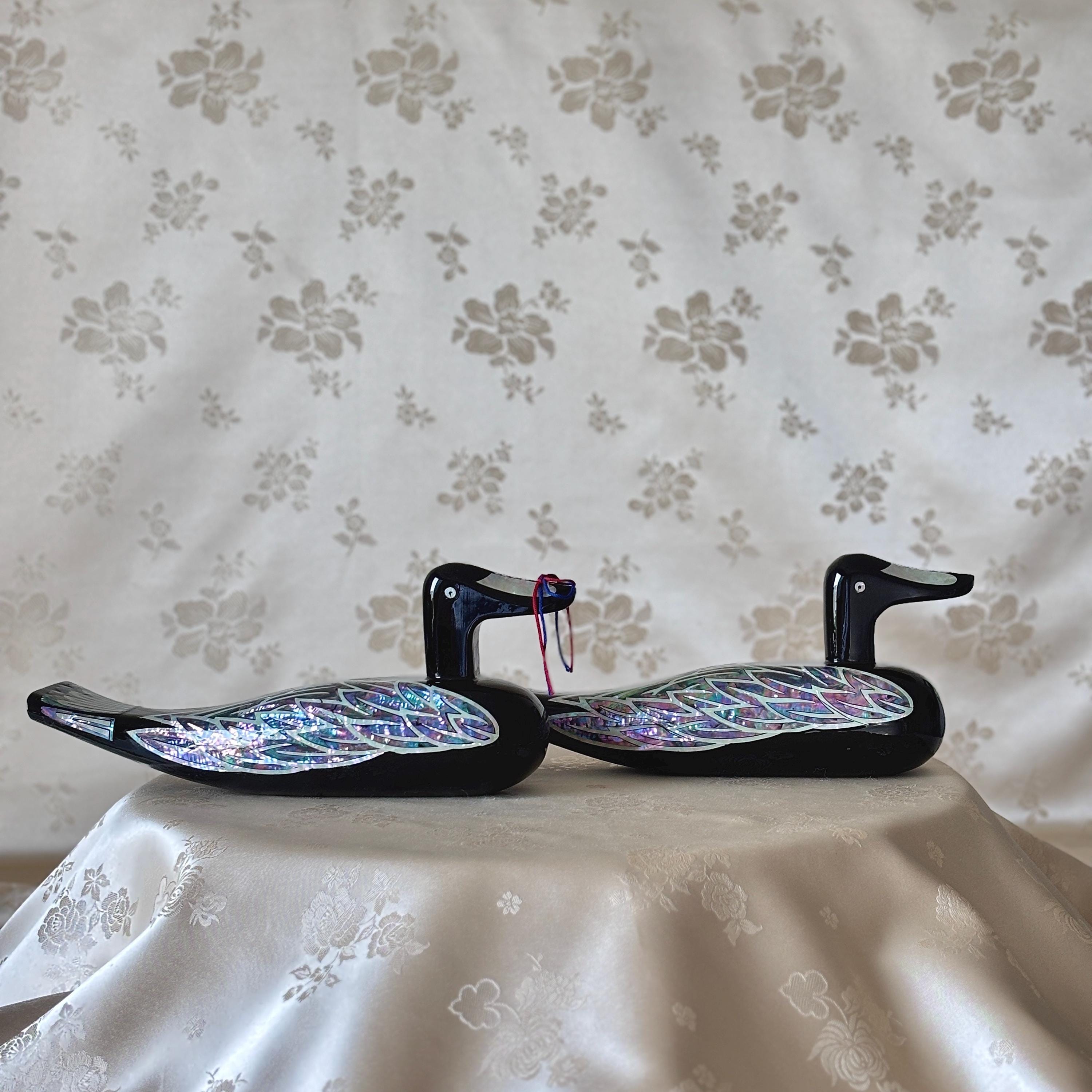 Large Korean mother-of-pearl wedding duck pair in black lacquer, displayed together on soft floral fabric