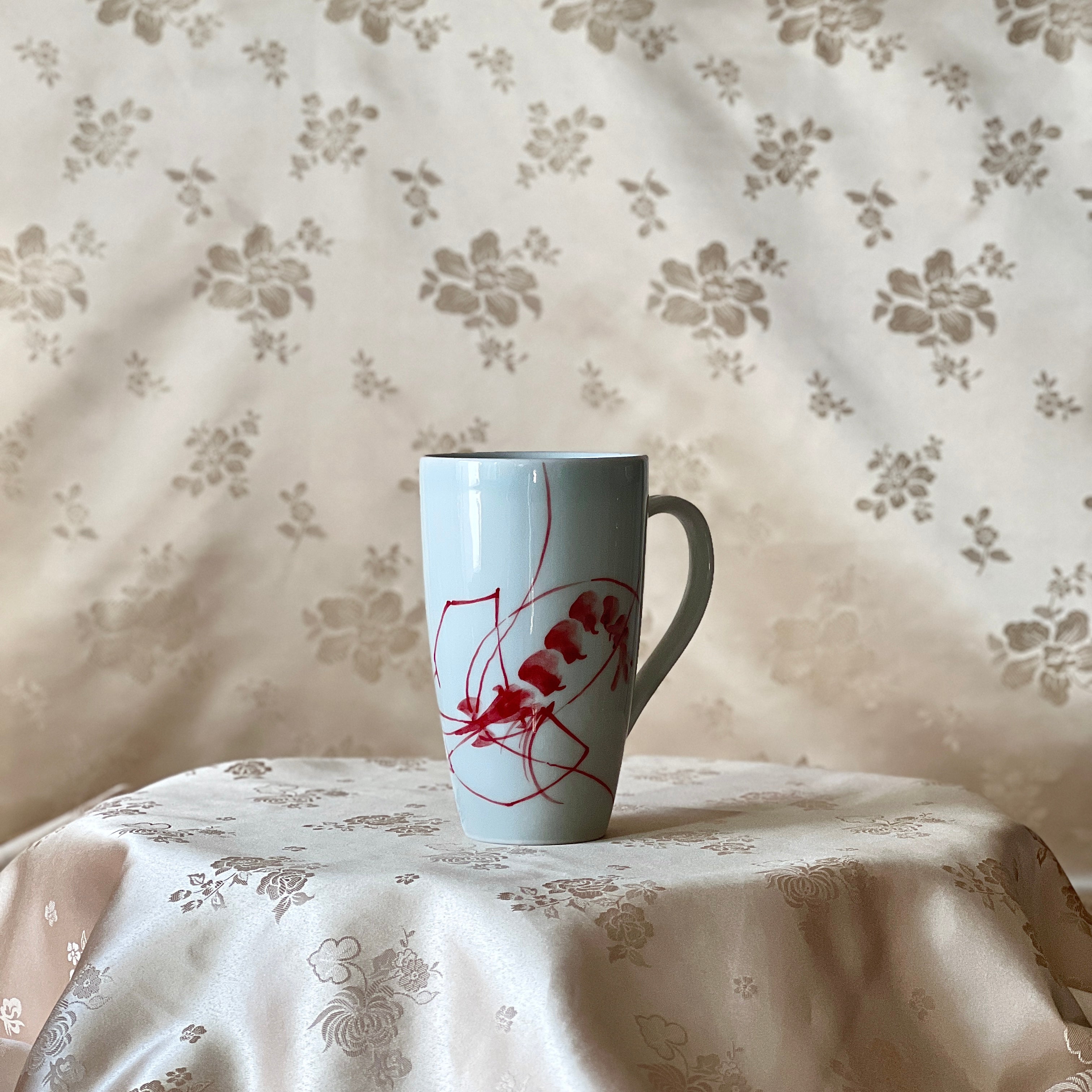 Korean white porcelain mug with red shrimp motif shown upright with handle visible
