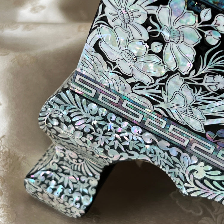 Close-up of the raised leg and corner of a Korean mother-of-pearl jewelry box with floral inlay