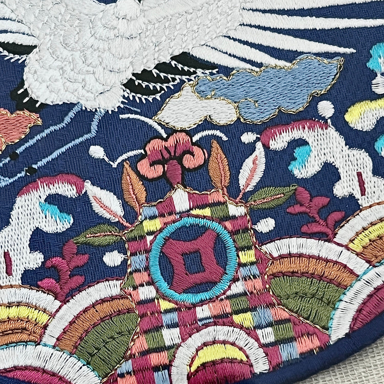 Close-up of an intricately embroidered fabric with colorful patterns and a bird design.