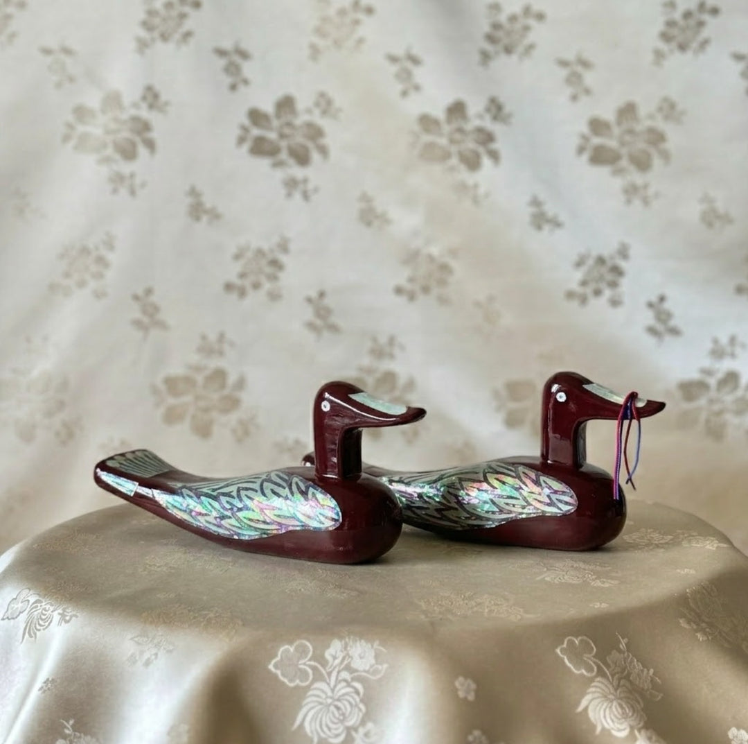 Korean mother-of-pearl wedding duck pair in wine red lacquer, displayed together on soft floral fabric