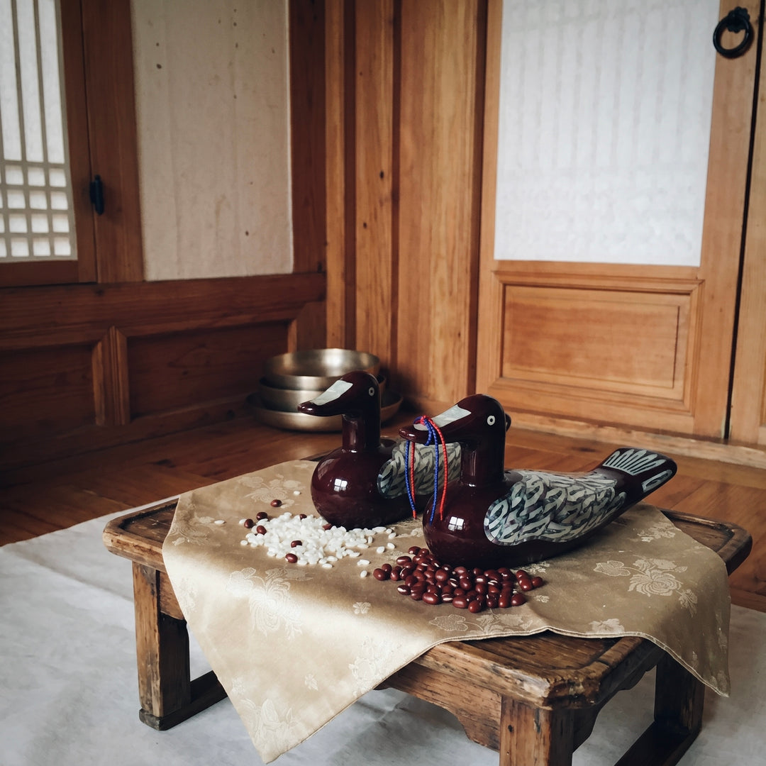 Korean mother-of-pearl wedding duck pair displayed in a traditional hanok-style interior setting