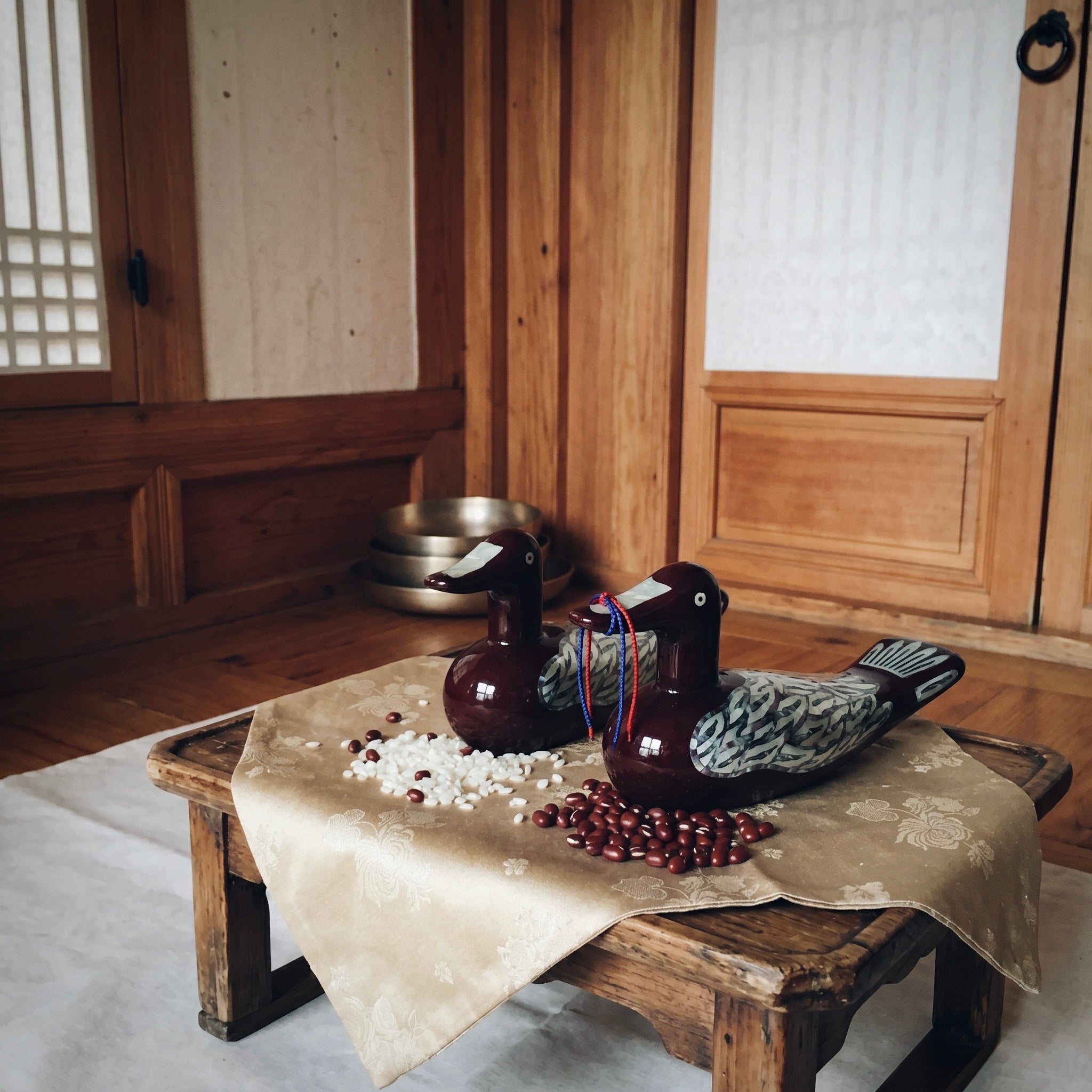 Korean mother-of-pearl wedding duck pair displayed in a traditional hanok-style interior setting