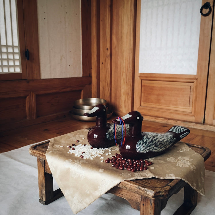 Korean mother-of-pearl wedding duck pair displayed in a traditional hanok-style interior setting