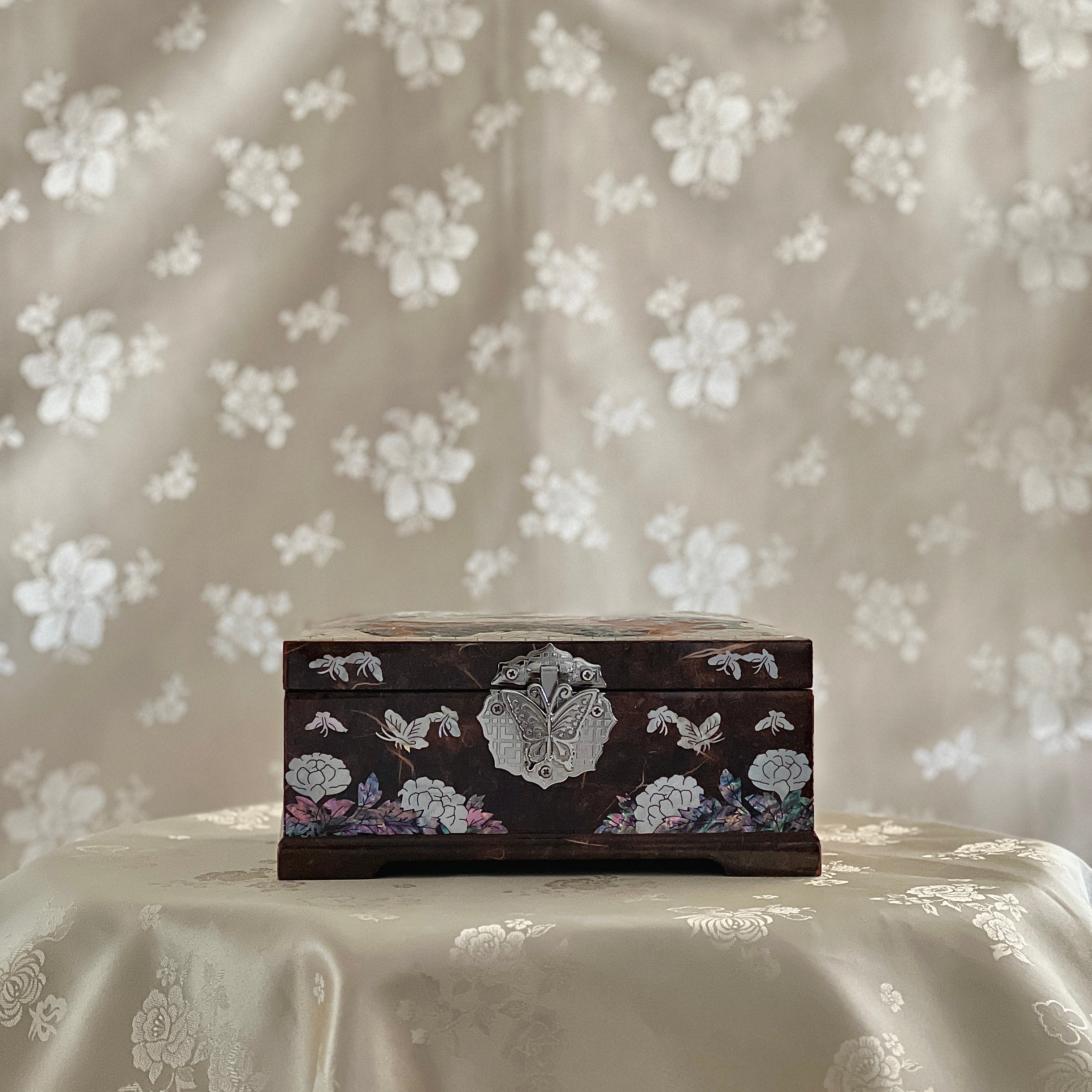 Decorative wooden box with floral patterns on a floral fabric background