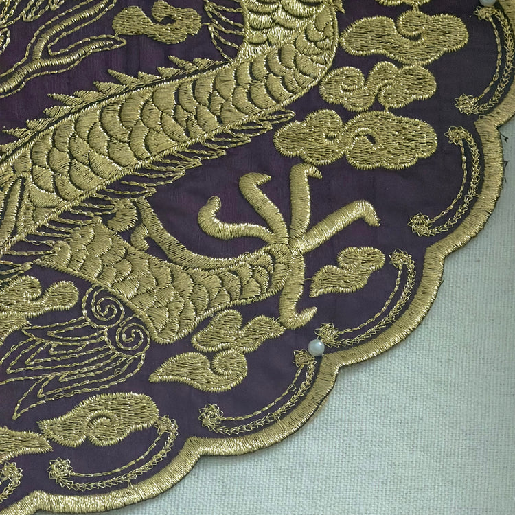 Close-up of gold embroidered dragon design on a dark fabric background