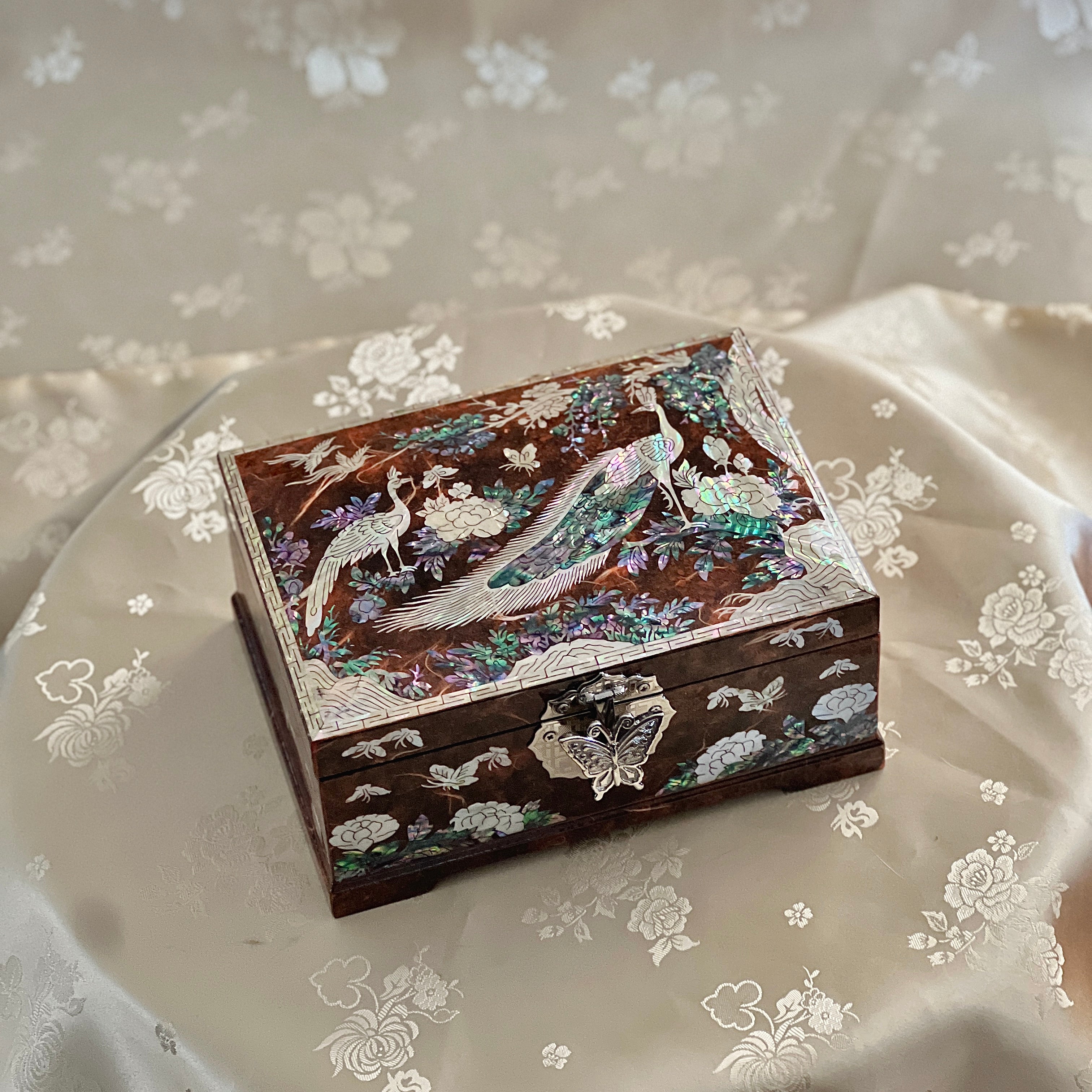 Decorative Korean jewelry box with intricate inlay on a floral fabric background mother of pearl