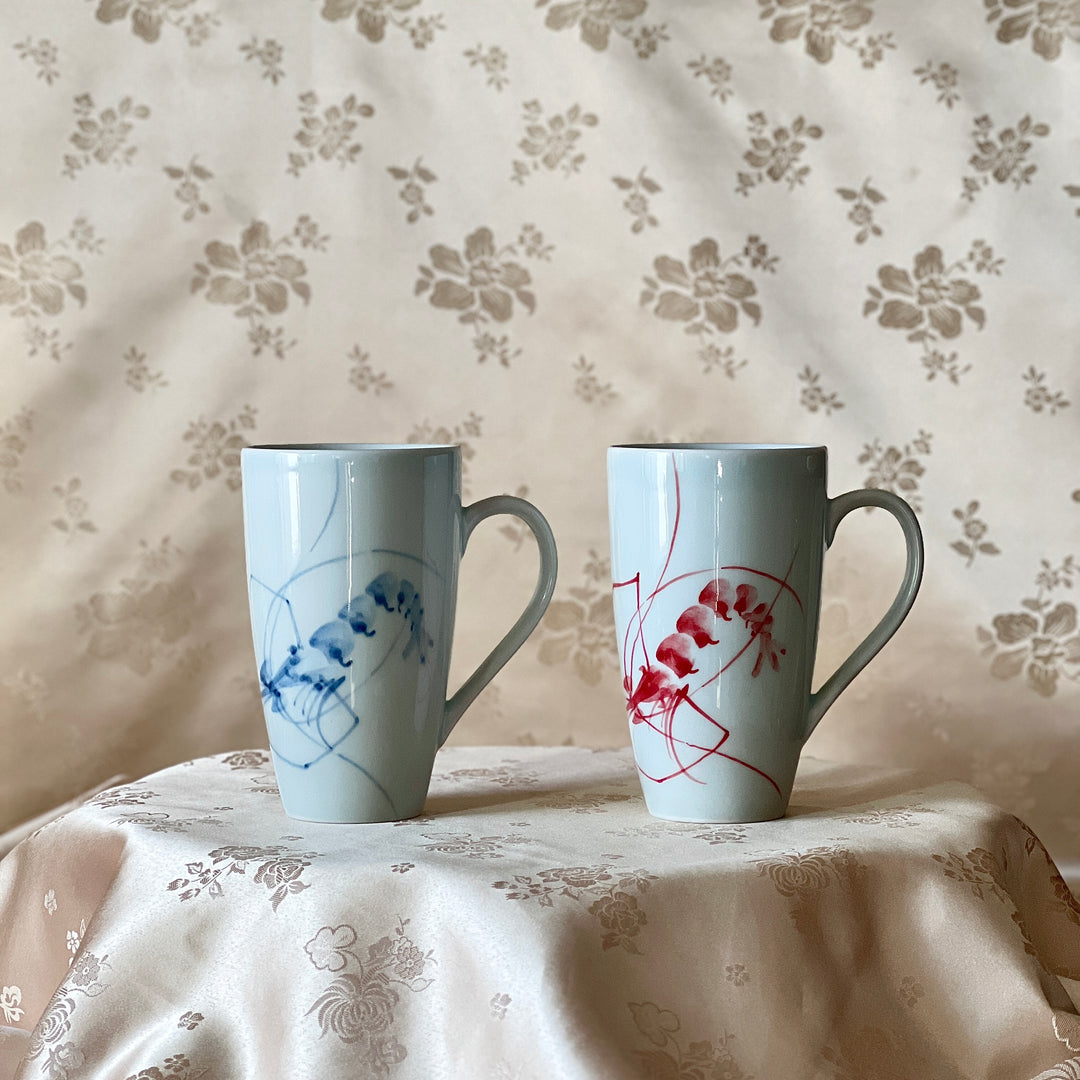 Korean white porcelain mug set with blue and red shrimp motifs displayed on soft floral fabric