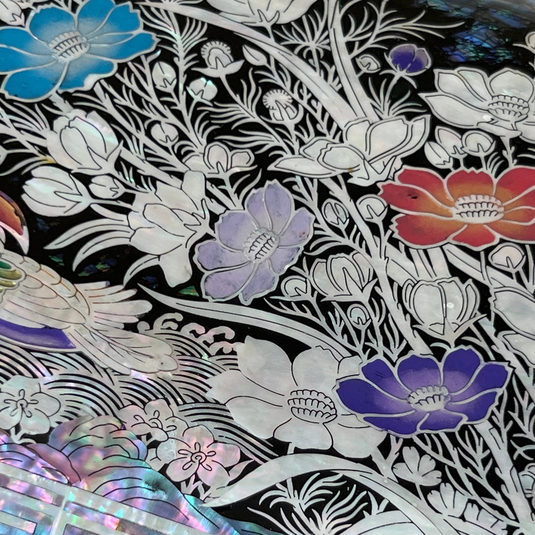 Close-up of colored mandarin duck and floral mother-of-pearl inlay on black lacquer