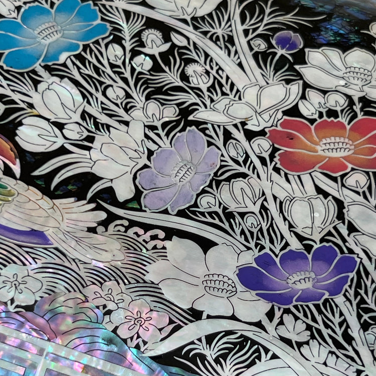 Close-up of colored mandarin duck and floral mother-of-pearl inlay on black lacquer