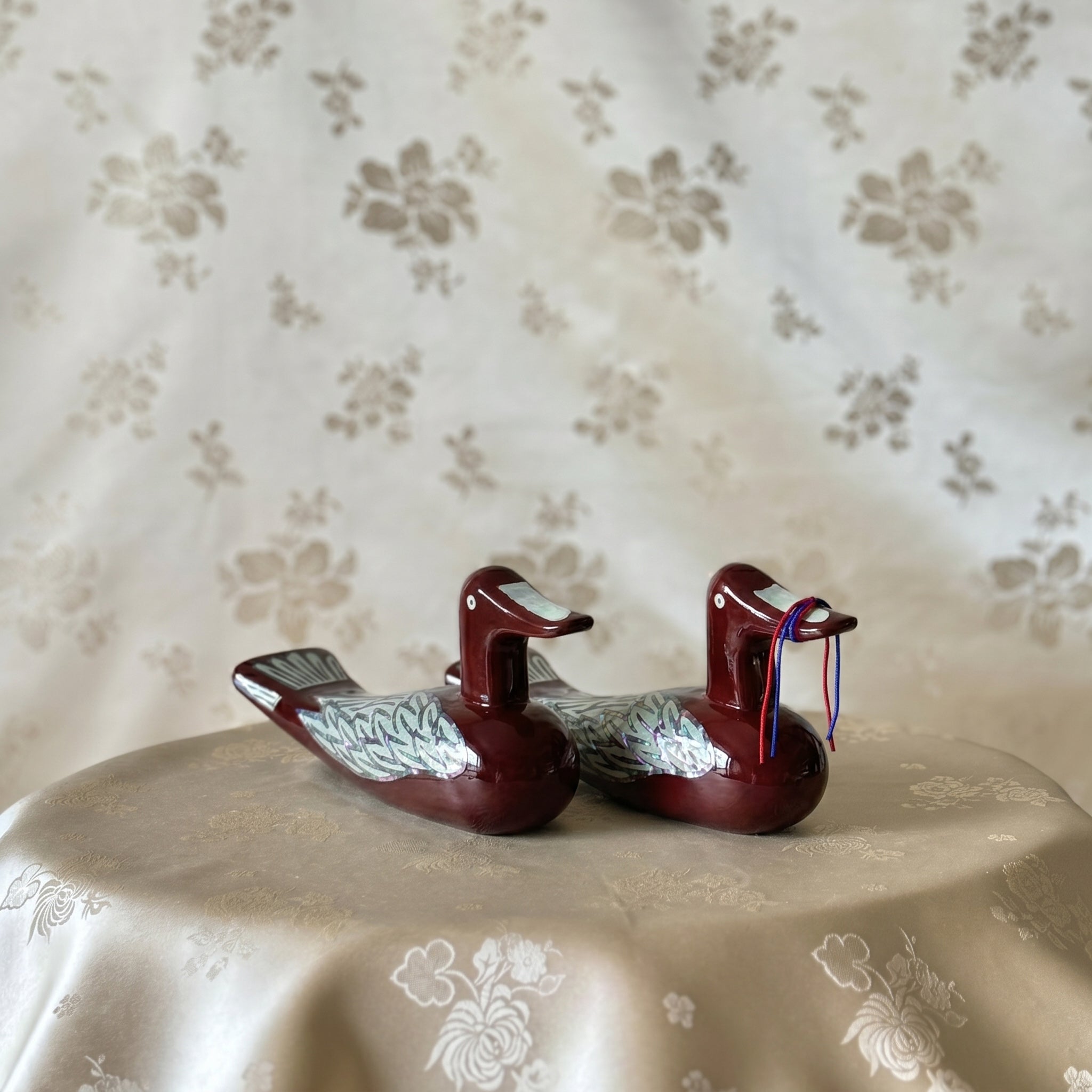 Pair of Korean mother-of-pearl wedding ducks with iridescent inlay on wine red bodies