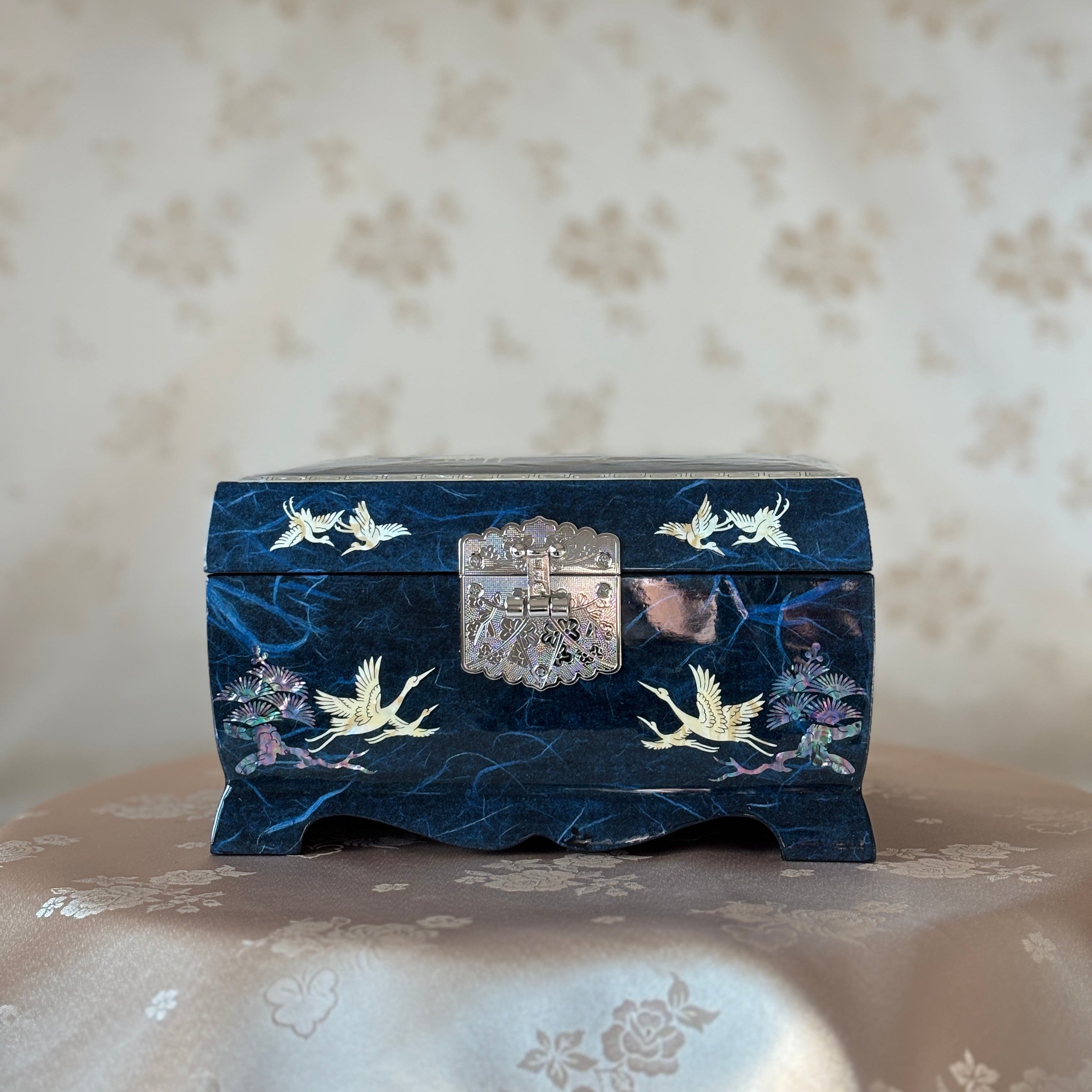 Decorative blue box with floral and bird patterns on a textured surface music box