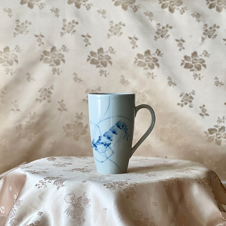Korean white porcelain mug with blue shrimp motif shown upright with handle visible