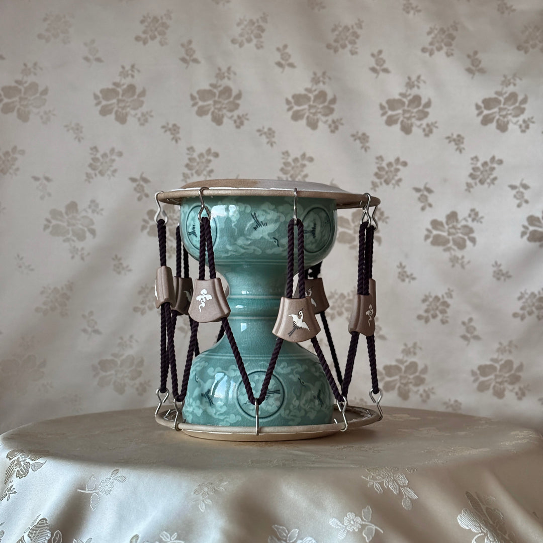 Turquoise cylindrical janggu with hanging elements on a silk background