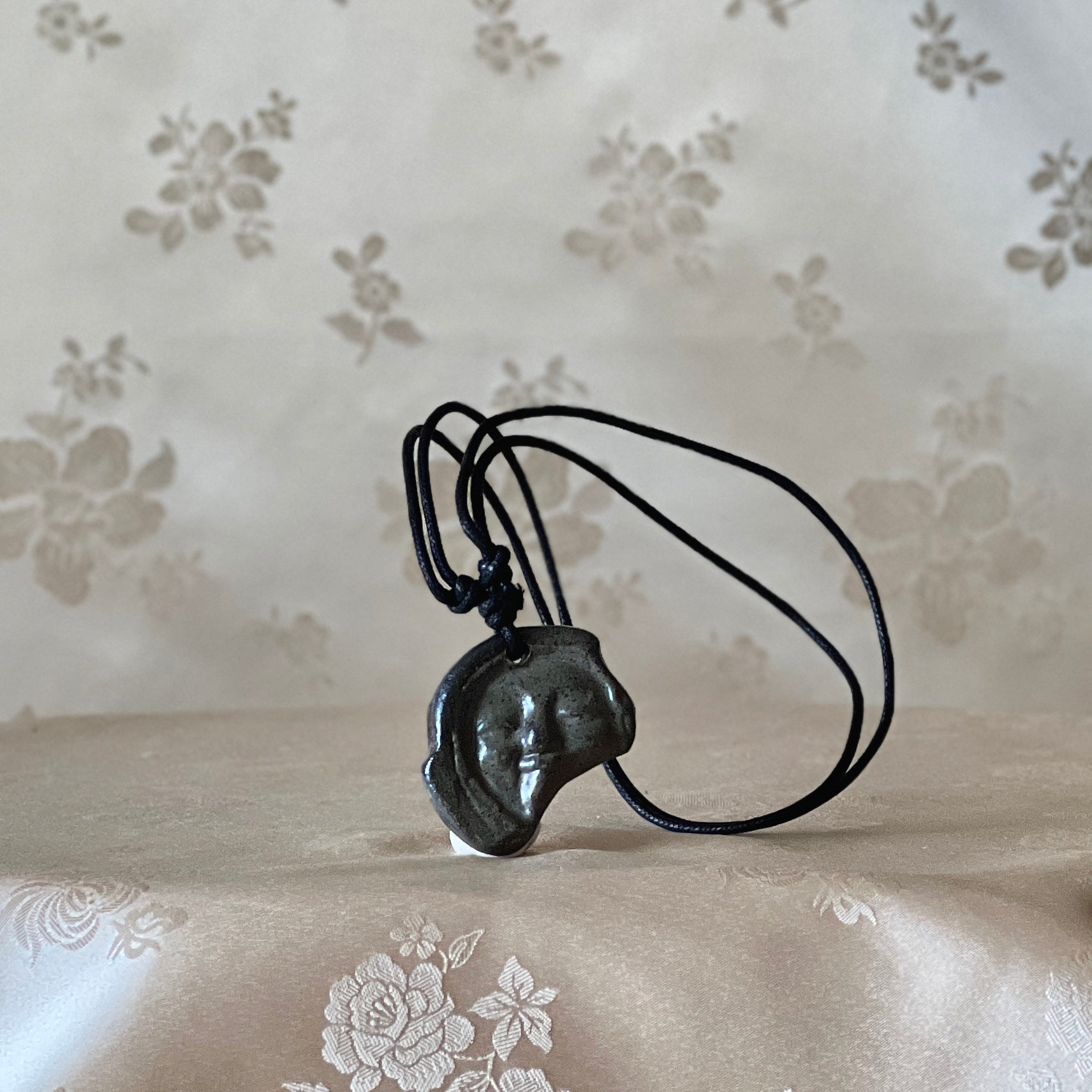 Korean Silla earthenware human-face Sumaksae pendant necklace shown from the front