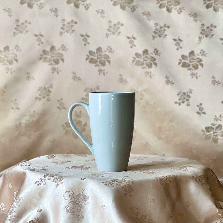 Back view of a Korean white porcelain mug showing the clean plain white surface and handle