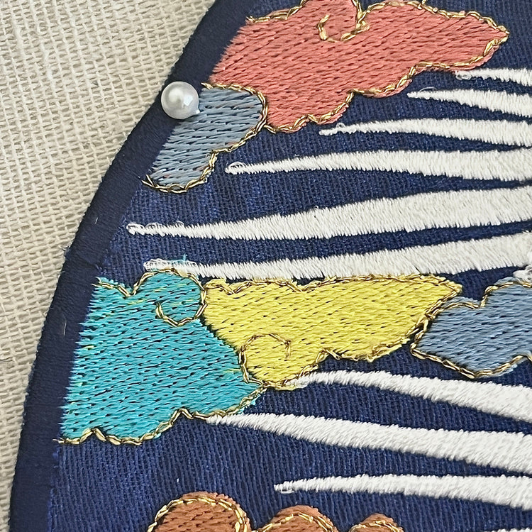 Embroidered fabric with colorful cloud patterns on a blue background