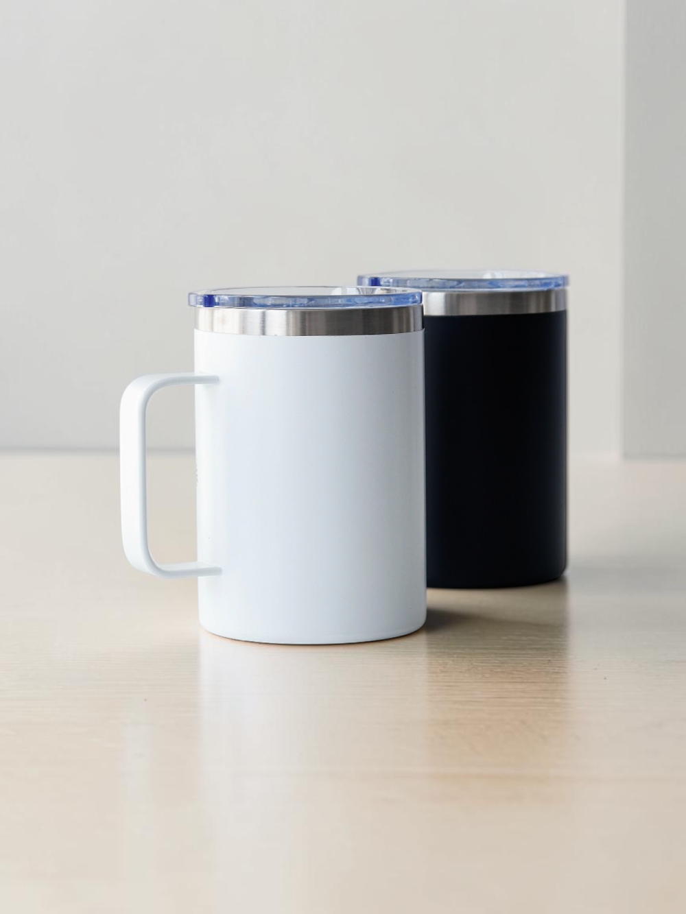 Back of White and black Korean mother of pearl mugs side by side, showing both color options with handles