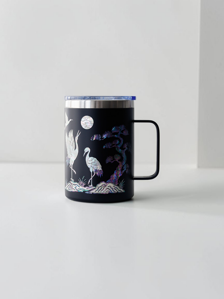 Black stainless mug with handle, mother of pearl cranes flying under a full moon with an inlaid pine tree