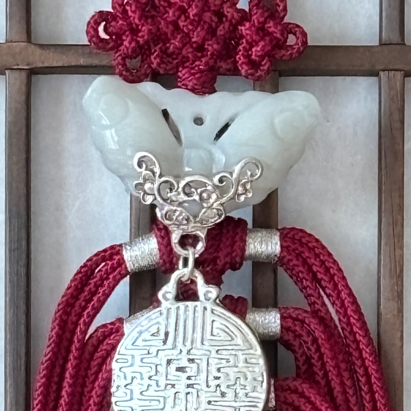 Decorative red tassels with silver embellishments on a wooden lattice background