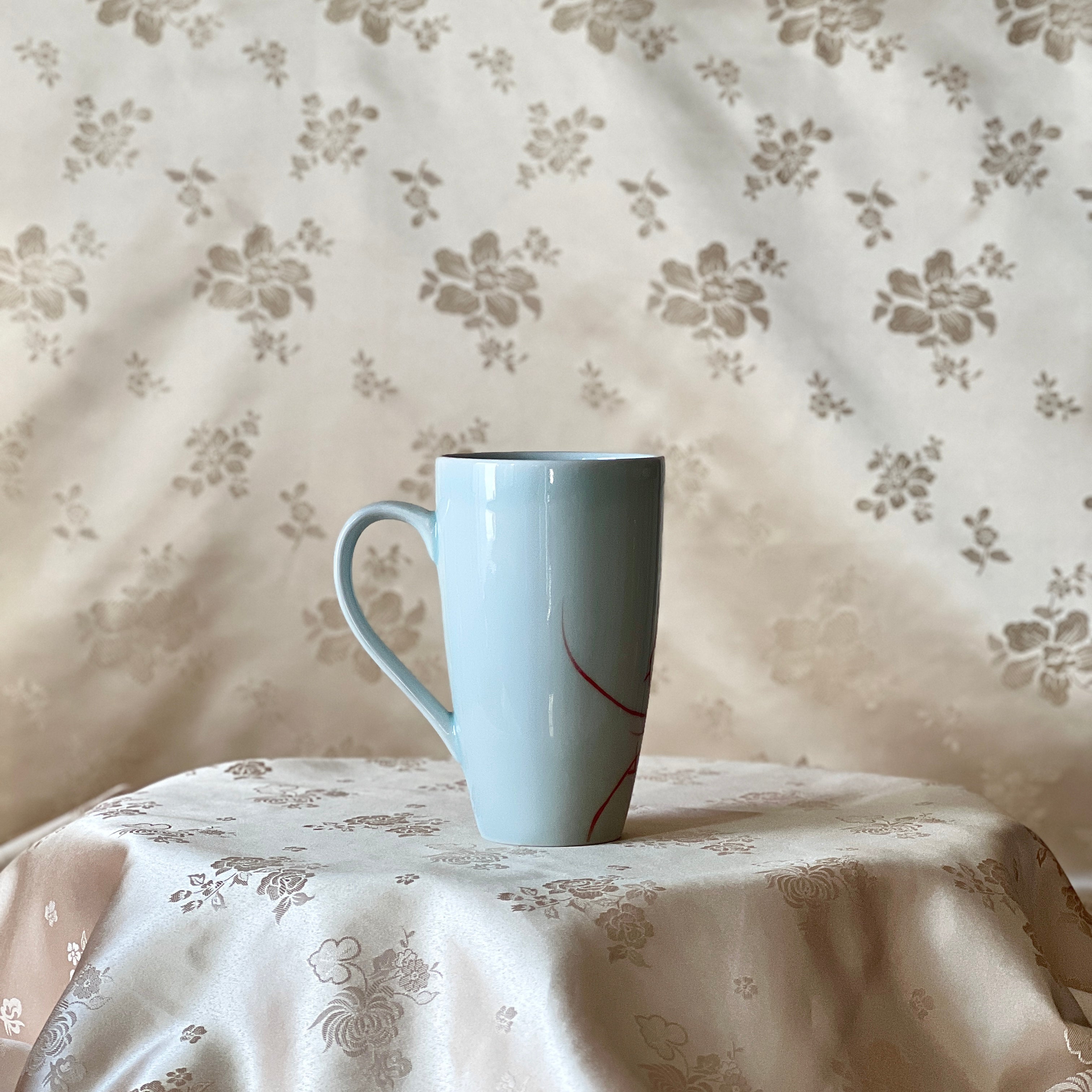 Back view of a Korean white porcelain mug showing the plain white surface and handle