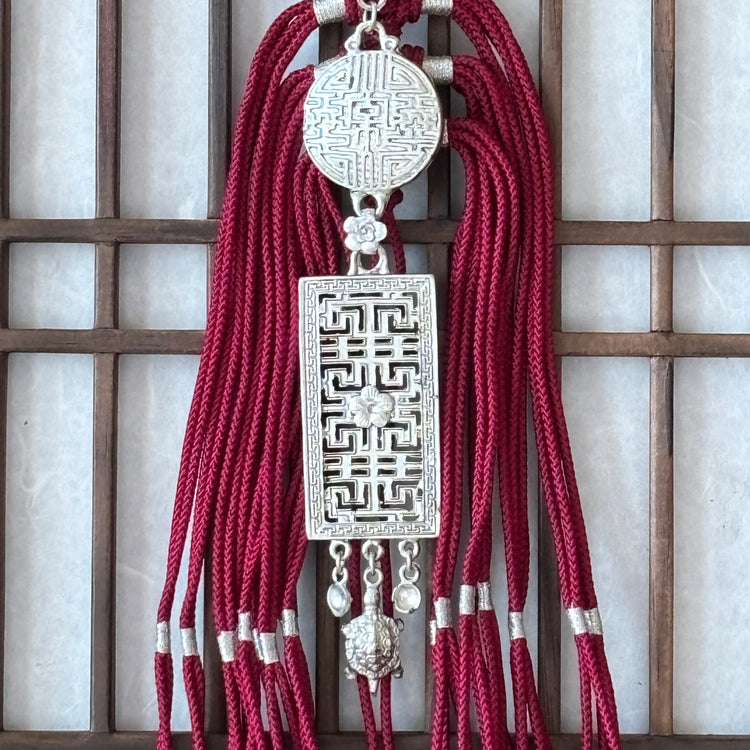 Decorative tassel with intricate design on a wooden lattice background