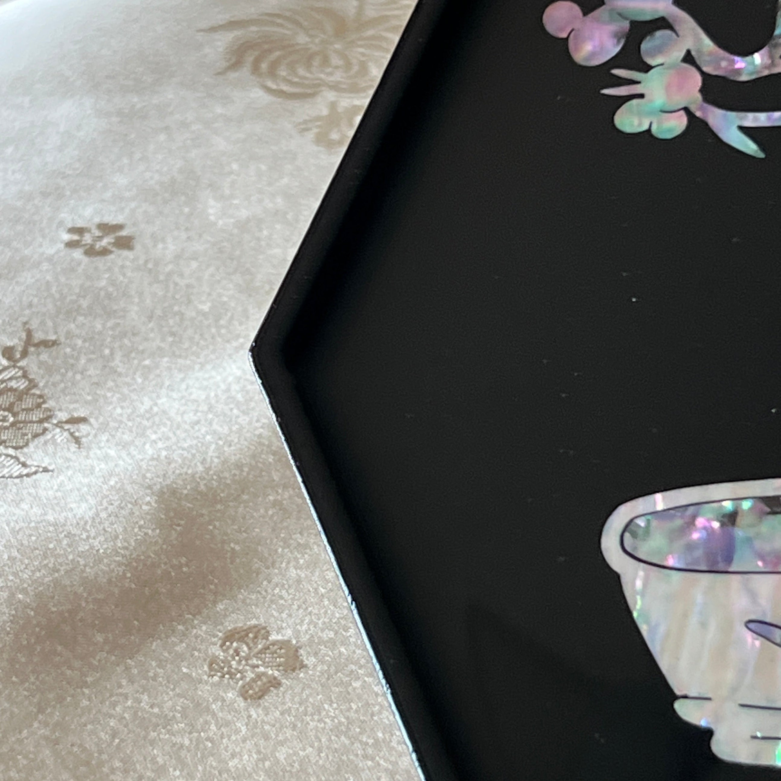 Close-up of najeonchilgi octagonal tray showing iridescent mother of pearl vase, cup, plum blossoms and crane