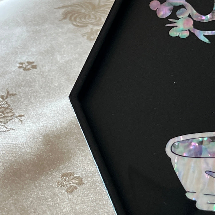 Close-up of najeonchilgi octagonal tray showing iridescent mother of pearl vase, cup, plum blossoms and crane