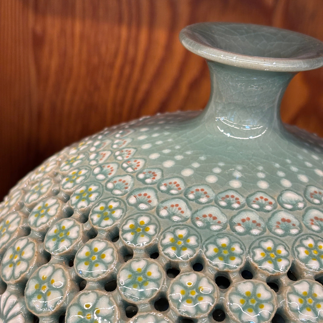 Cracked pattern celadon ceramic vase with floral pattern on a wooden surface