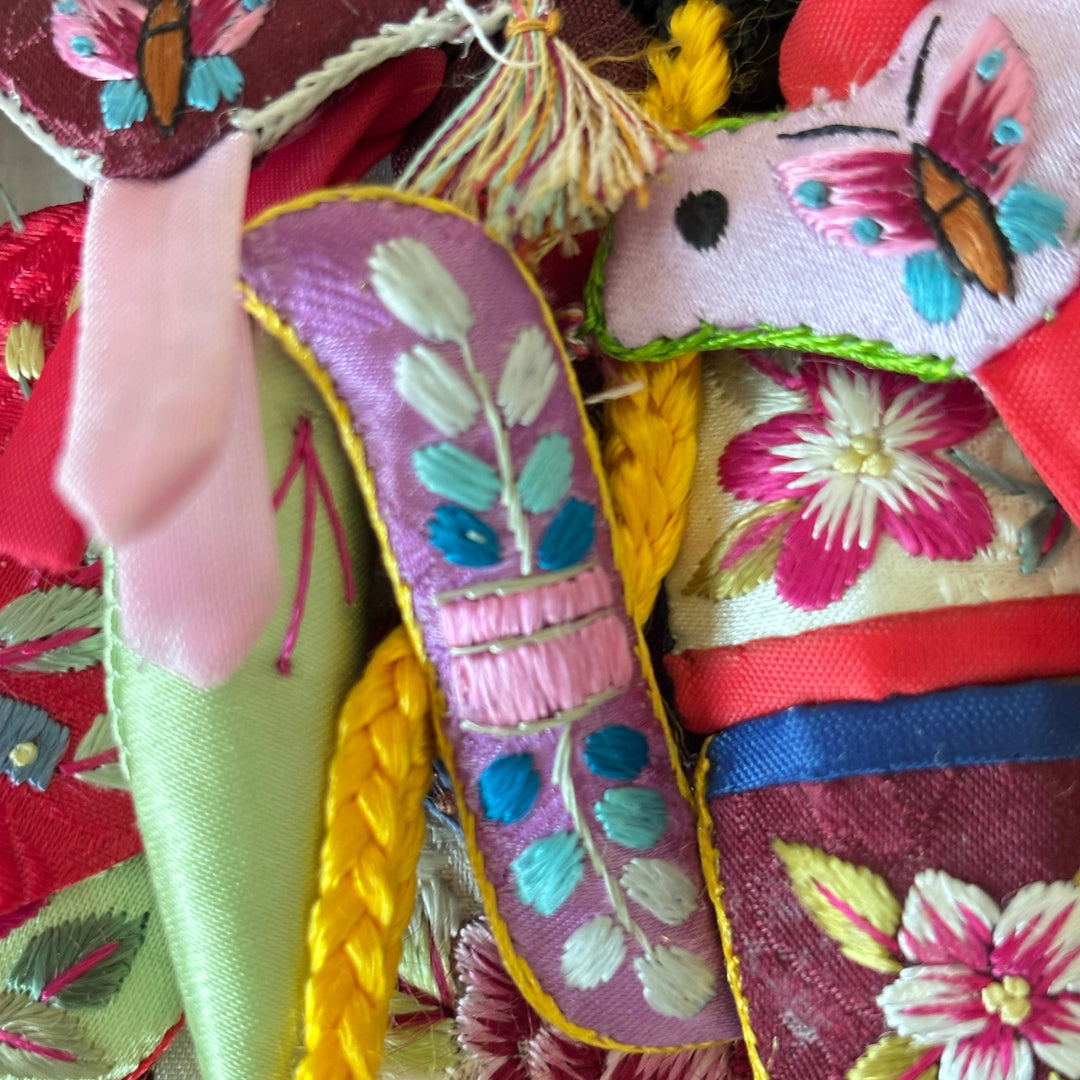 Colorful embroidered fabric with floral patterns and a hand holding it.
