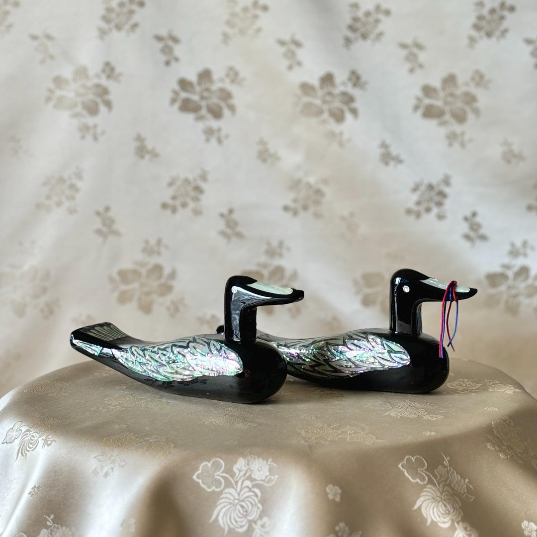 Korean mother-of-pearl wedding duck pair in black lacquer, displayed together on soft floral fabric