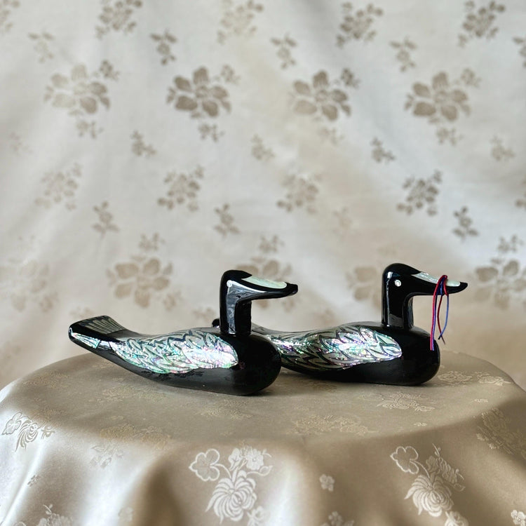 Korean mother-of-pearl wedding duck pair in black lacquer, displayed together on soft floral fabric