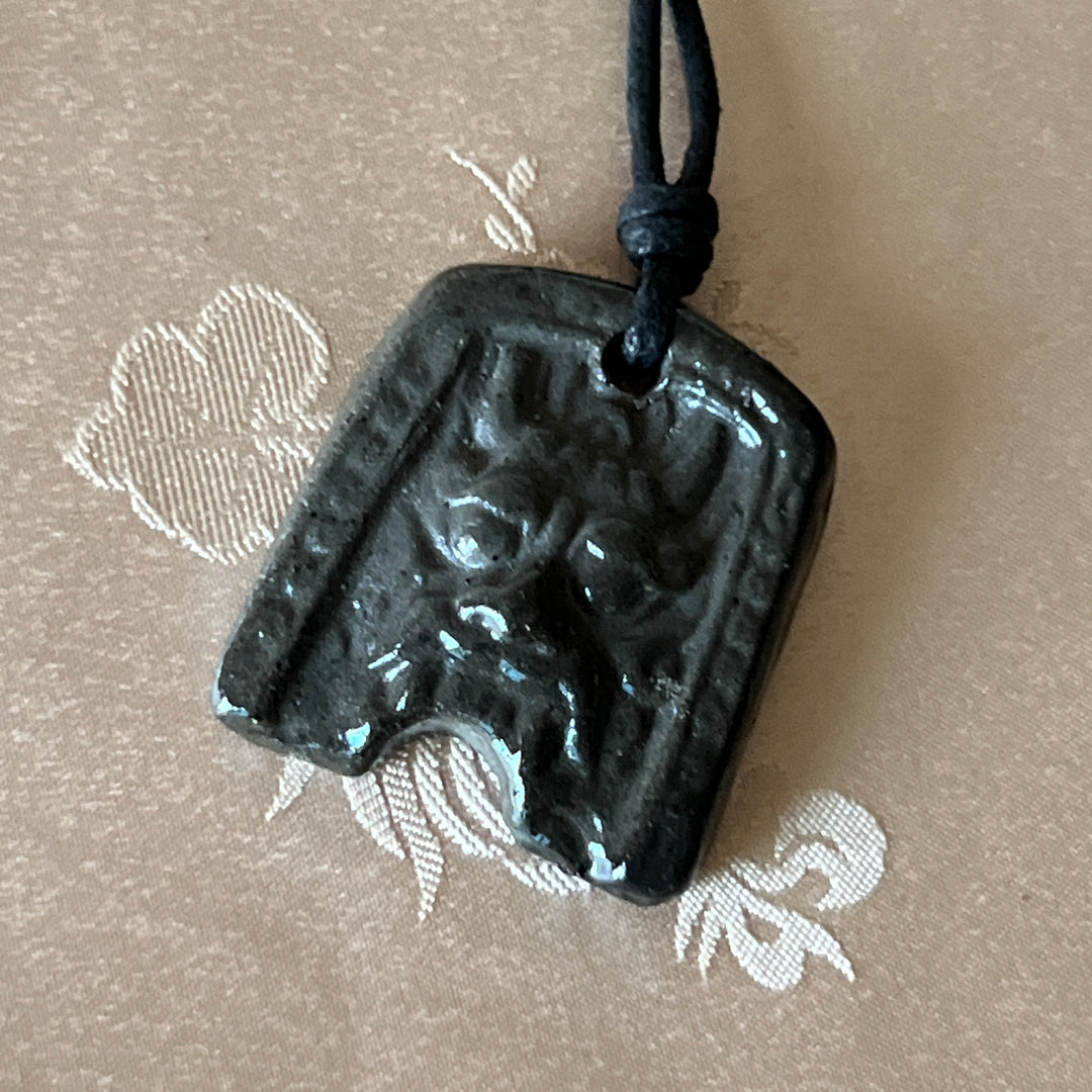Korean Silla earthenware Gwimyeonwa demon-face pendant with protective mask motif and black cord