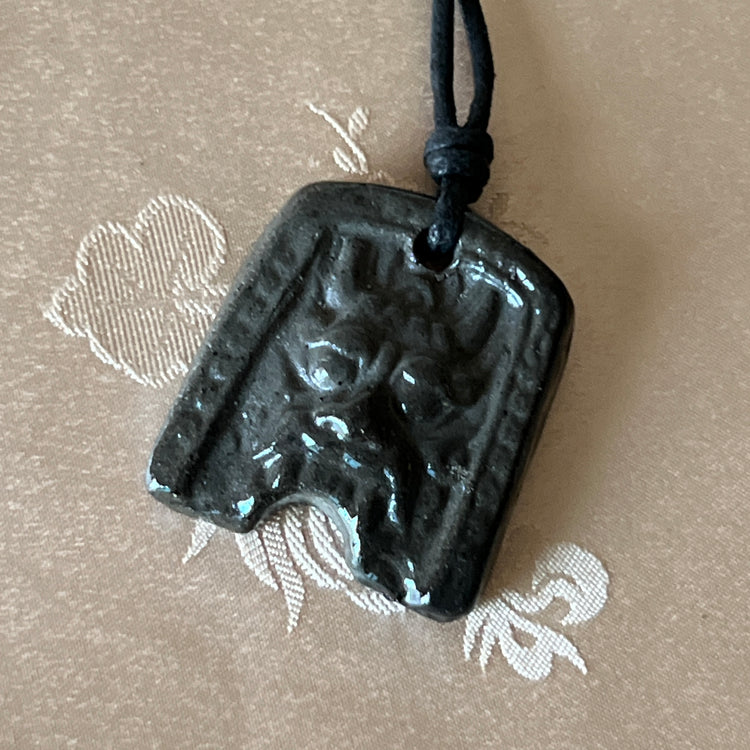 Korean Silla earthenware Gwimyeonwa demon-face pendant with protective mask motif and black cord