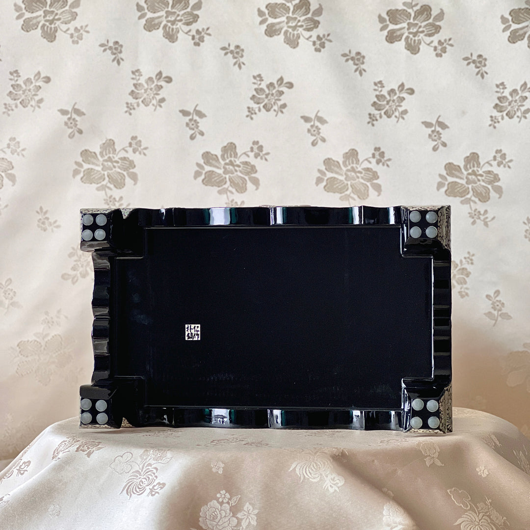 Underside view of a Korean mother-of-pearl jewelry box showing the black lacquer base and raised feet