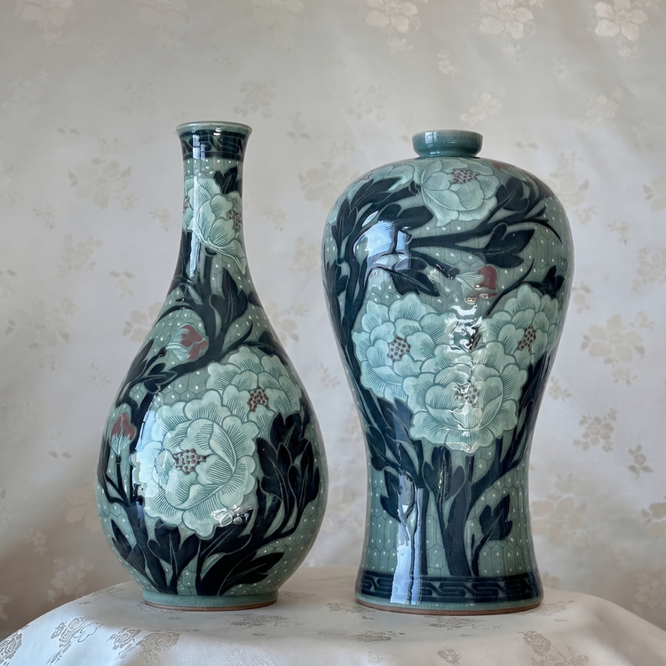 Two ceramic vases with floral patterns on a textured surface.