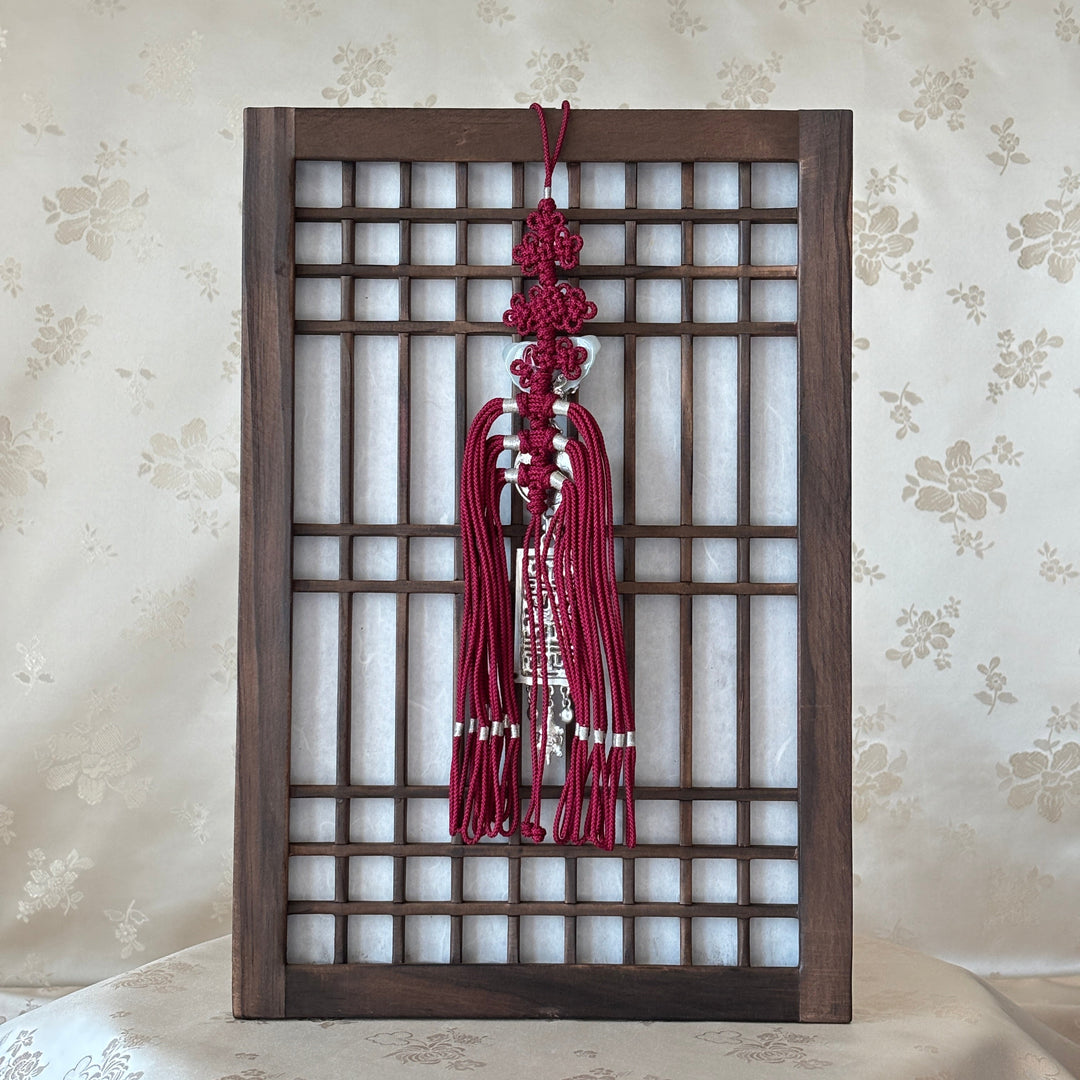 Decorative red tassels hanging from a wooden lattice against a floral wallpaper background