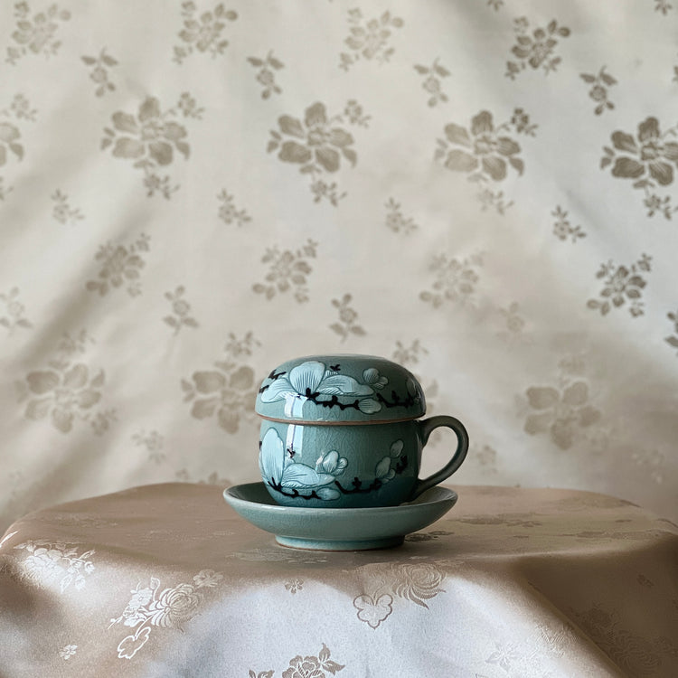 Tea cup and saucer with floral design on a floral-patterned tablecloth