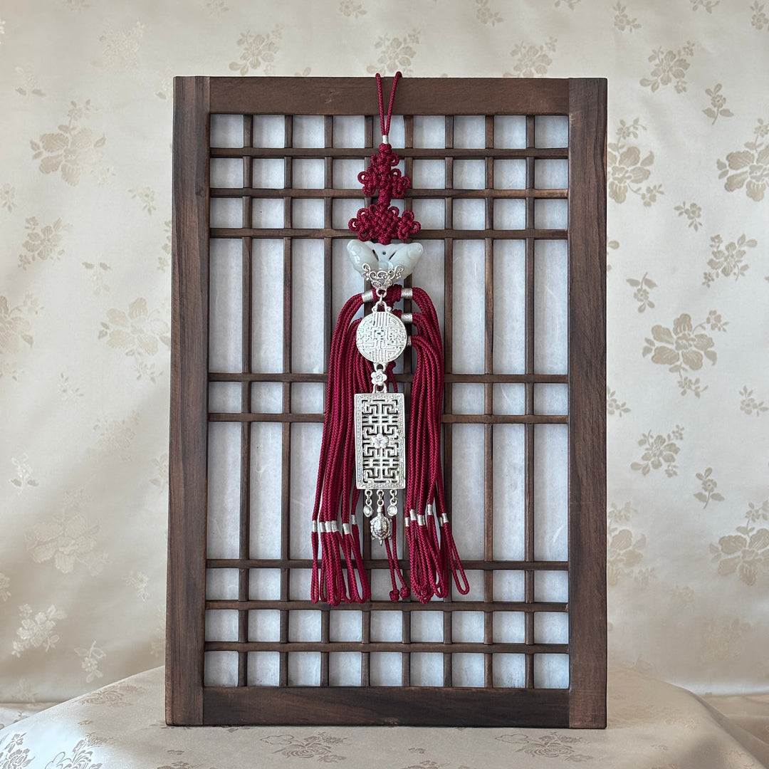 Korean traditional wall art hanging with a metal design on a floral wallpaper background