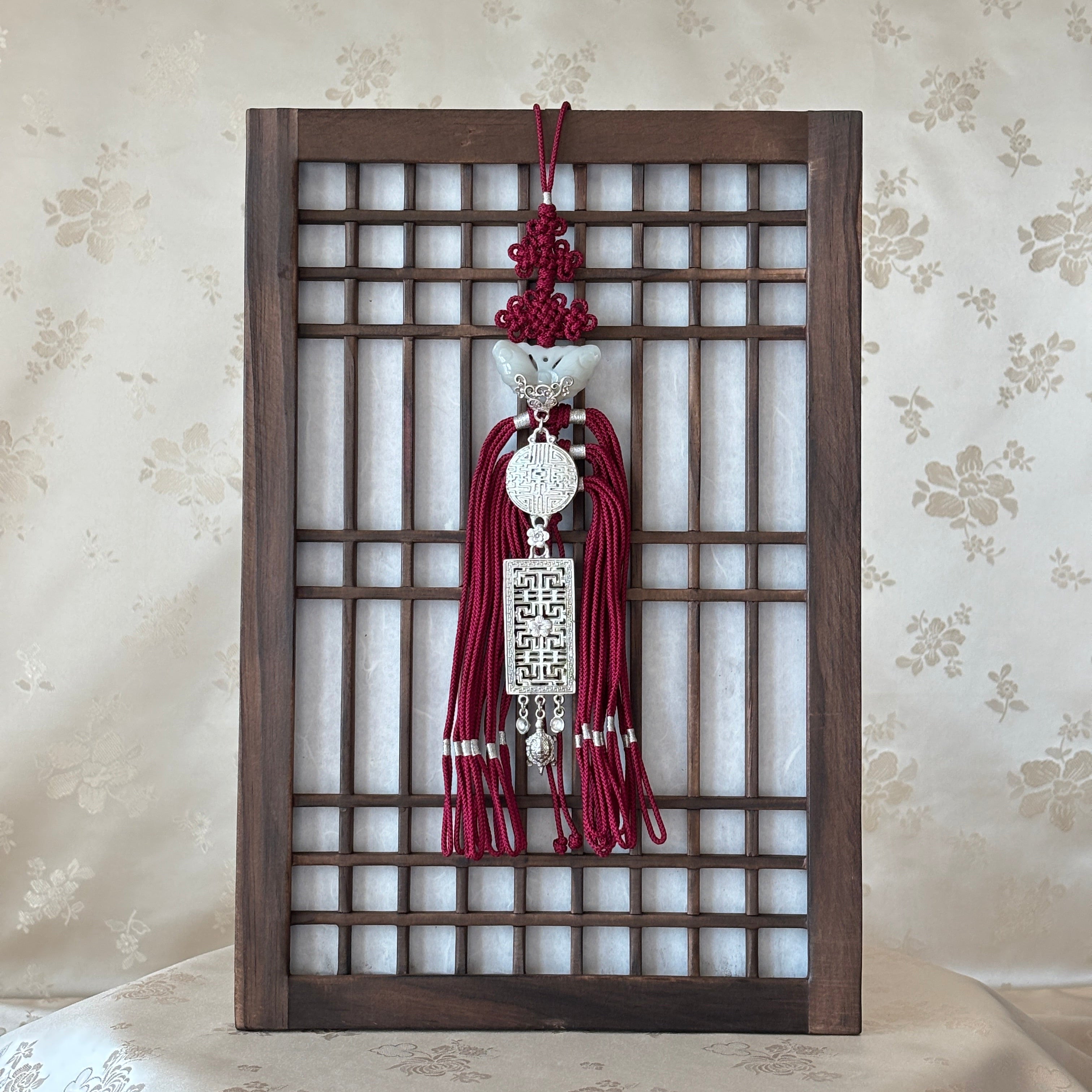 Korean traditional wall art hanging with a metal design on a floral wallpaper background