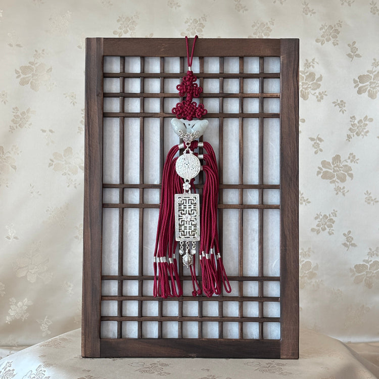 Korean traditional wall art hanging with a metal design on a floral wallpaper background
