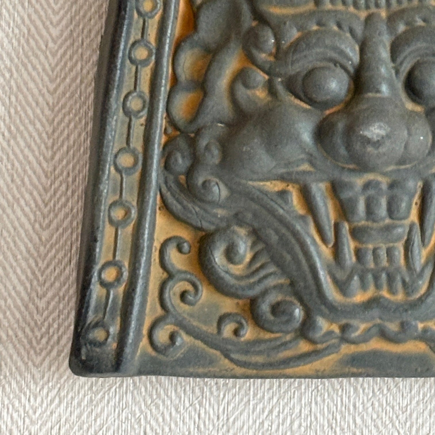 Decorative wall plaque with intricate design on a textured beige wall